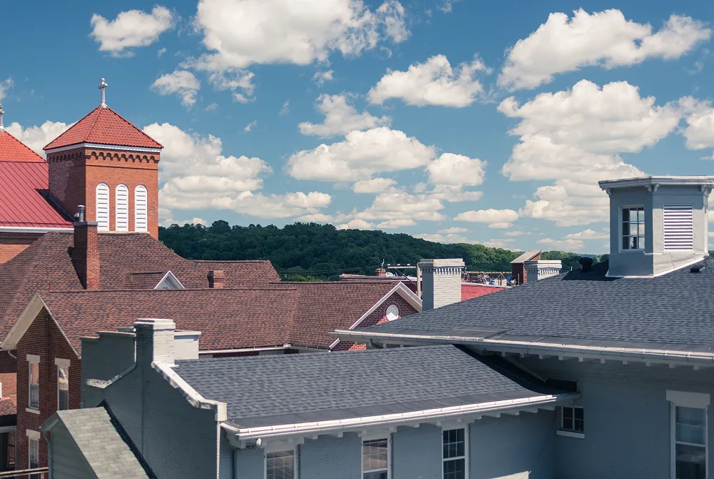 Rooflines of older downtown brick buildings with low-slope roof sections between the gables